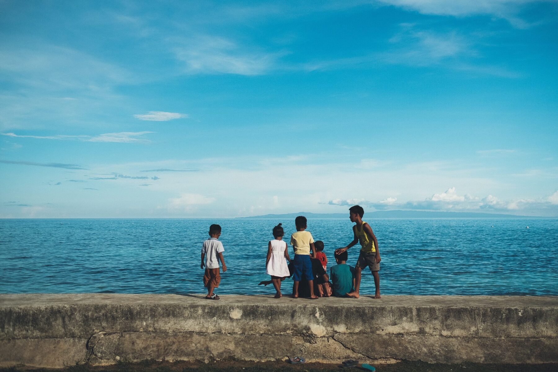 Children at the waterβs edge, smiling, in a coastal village